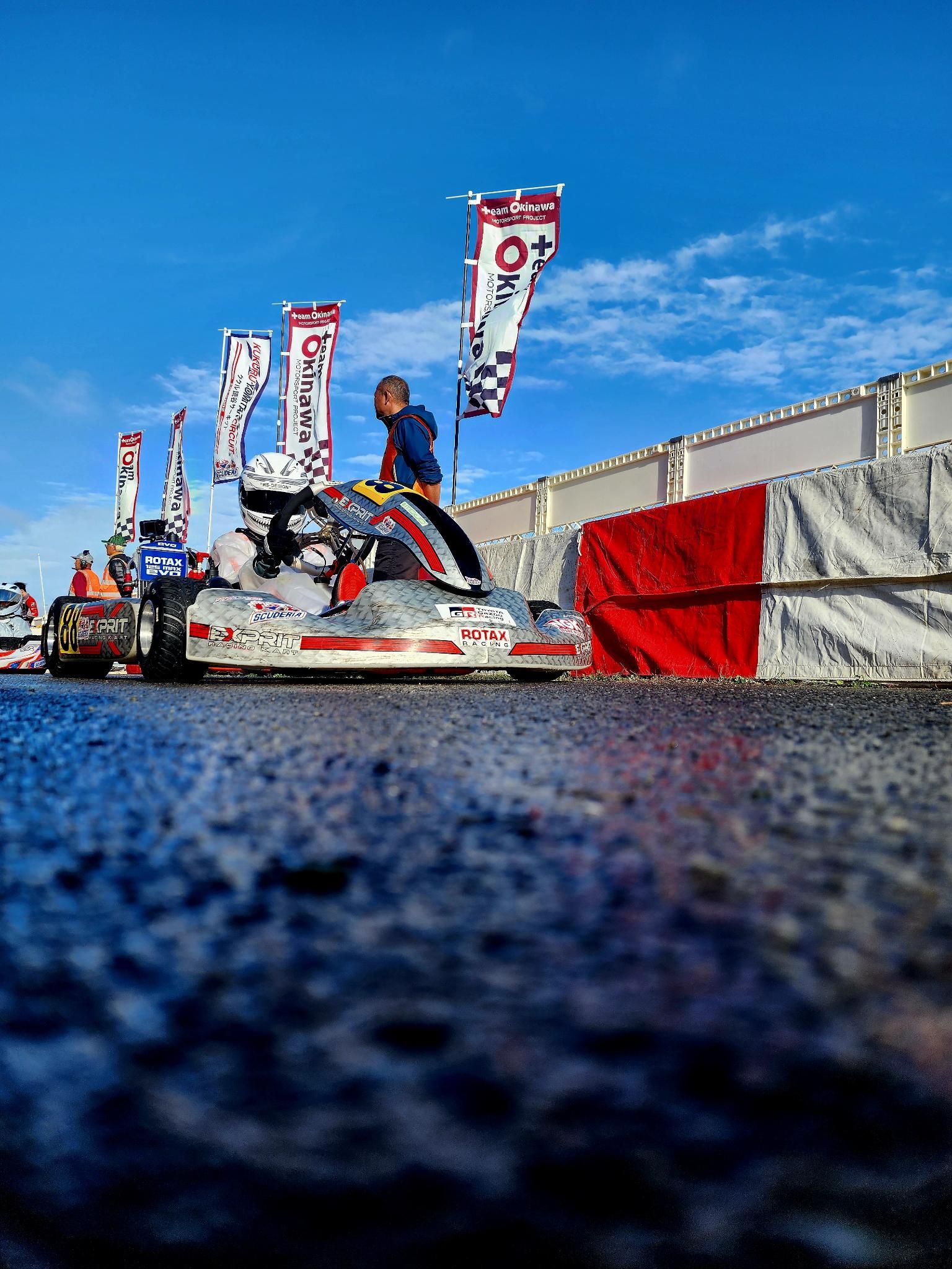 Kart 88 on the grid beside Team Okinawa flags before a race