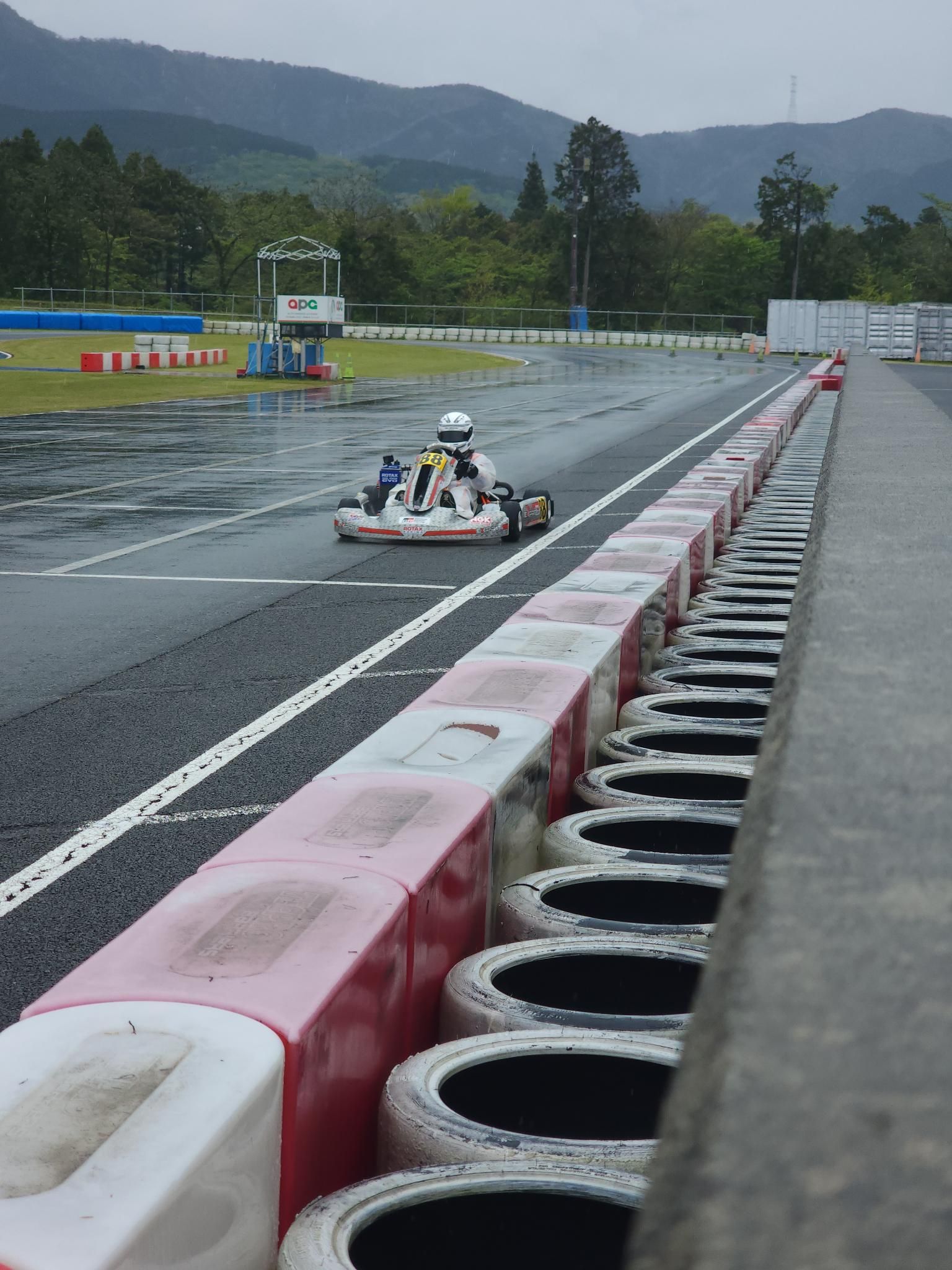 Kart 88 cornering on a wet track in the rain with mountains behind